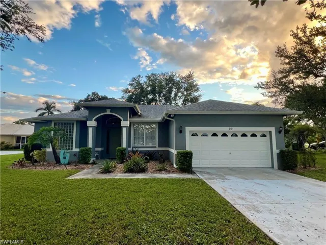 Stucco exterior with a tiled roof, featuring a two-car garage, concrete driveway, and front landscaping