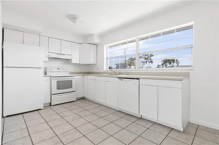 Kitchen with sink, a wealth of natural light, white cabinets, and white appliances