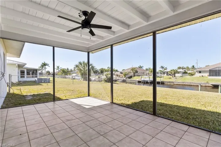 Unfurnished sunroom with beamed ceiling, a water view, and ceiling fan