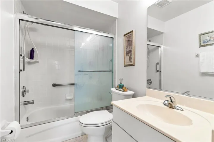 Full bathroom featuring vanity, bath / shower combo with glass door, and toilet