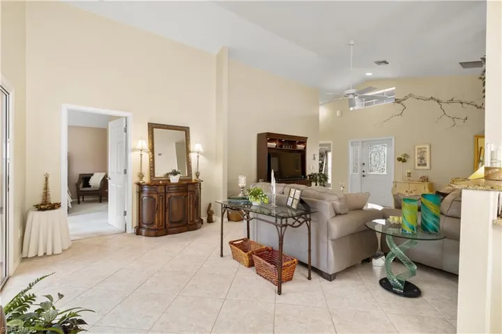 Tiled living room with ceiling fan and high vaulted ceiling