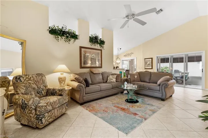 Living room with ceiling fan, light tile patterned floors, and high vaulted ceiling