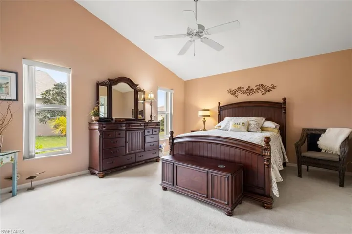 Bedroom with light carpet, vaulted ceiling, and ceiling fan
