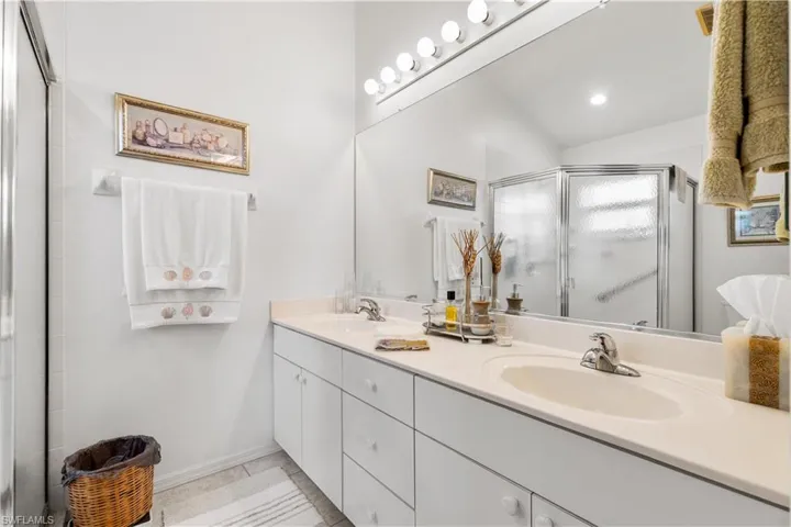 Bathroom featuring vanity, tile patterned floors, an enclosed shower, and lofted ceiling