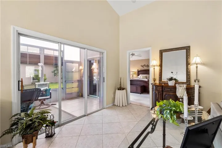 Doorway with ceiling fan, light tile patterned floors, and high vaulted ceiling