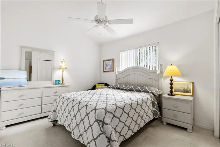 Carpeted bedroom with ceiling fan and lofted ceiling