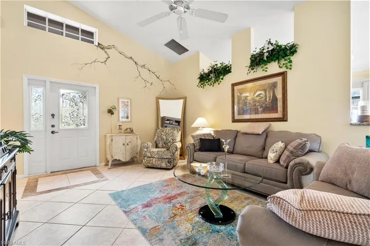 Tiled living room with ceiling fan and high vaulted ceiling