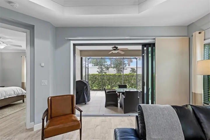 Living room with a tray ceiling, wood-type flooring, and ceiling fan