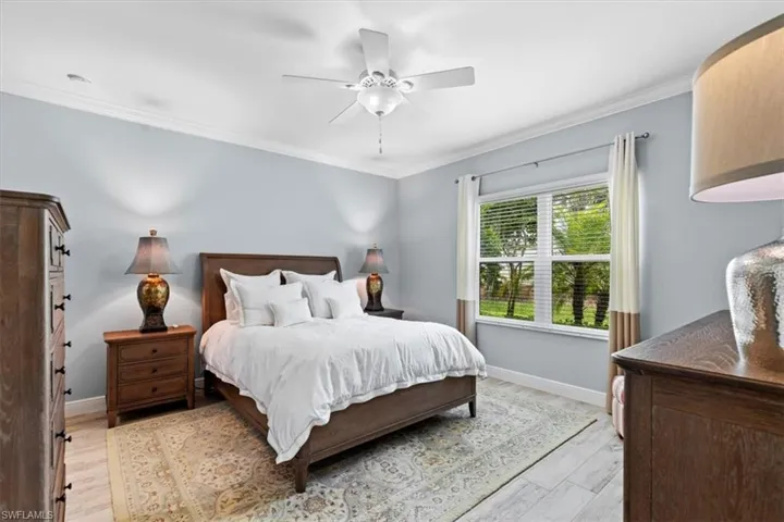 Bedroom with ceiling fan, hardwood / wood-style flooring, and ornamental molding