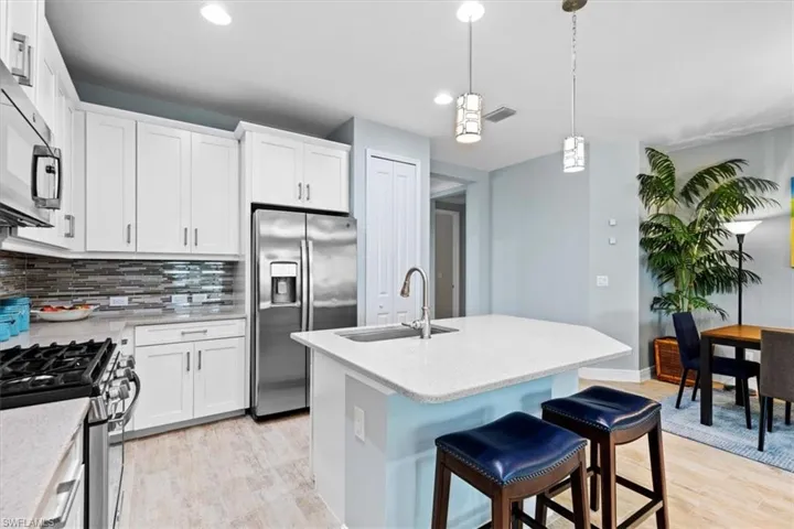 Kitchen featuring decorative light fixtures, stainless steel appliances, decorative backsplash, sink, and light hardwood / wood-style flooring