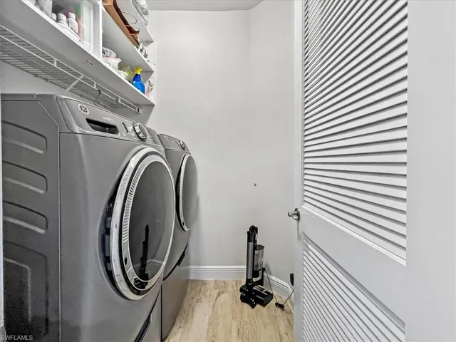 Washroom with washer and dryer and light wood-type flooring