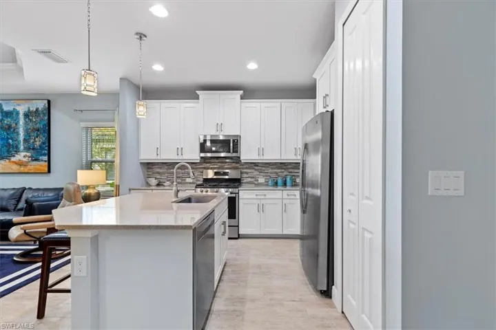 Kitchen featuring white cabinets, stainless steel appliances, tasteful backsplash, and sink