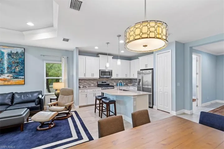 Kitchen featuring a breakfast bar, tasteful backsplash, a kitchen island with sink, stainless steel appliances, and hanging light fixtures
