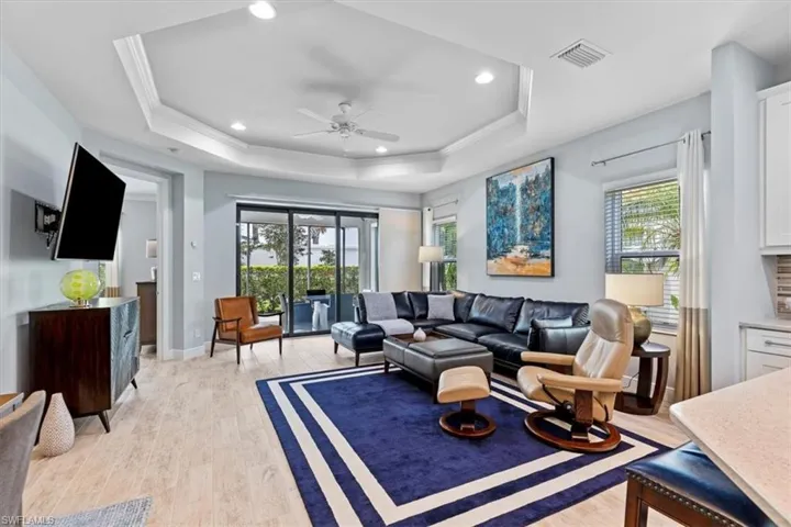Living room featuring ceiling fan, crown molding, light wood-type flooring, and a tray ceiling