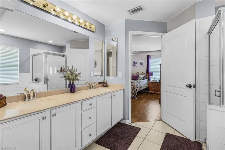 Bathroom featuring a stall shower, double vanity, ensuite bathroom, and tile patterned flooring