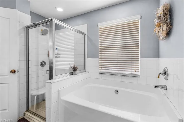 Bathroom featuring a bath, a shower stall, and recessed lighting