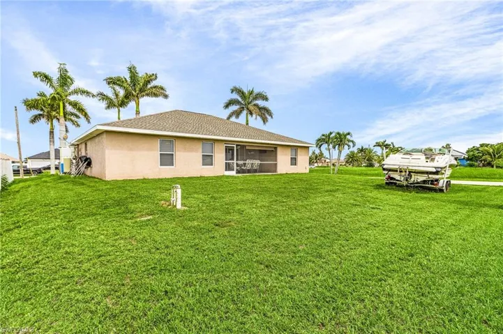 Back of house with stucco siding and a lawn