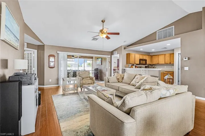 Living room with lofted ceiling, a ceiling fan, and wood finished floors