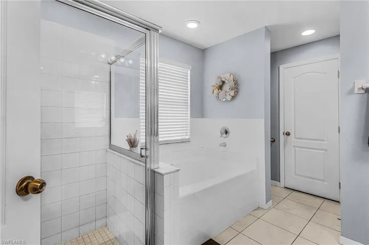Full bath featuring tile patterned floors, a bath, and a shower stall