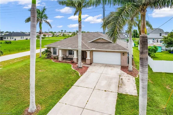 Ranch-style house featuring an attached garage, driveway, a shingled roof, stucco siding, and a residential view