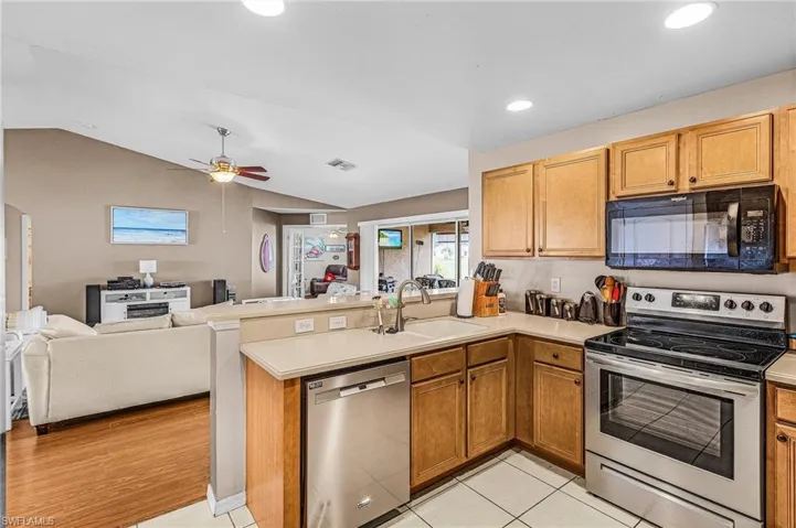 Kitchen with stainless steel appliances, a peninsula, light countertops, open floor plan, and a ceiling fan