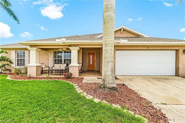 Single story home featuring covered porch, a front lawn, driveway, and stucco siding