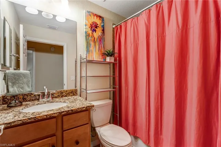 Bathroom featuring toilet, vanity, and a shower with curtain