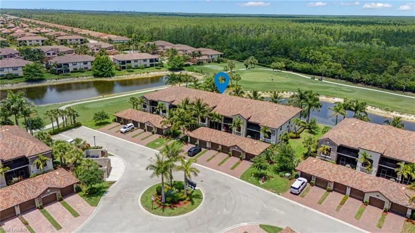 Aerial view of residential area featuring a forest, a nearby body of water, and a golf course