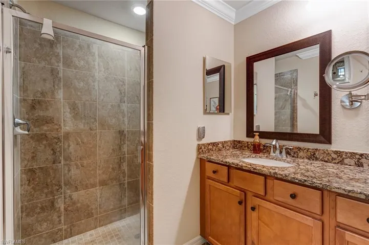 Full bath with a stall shower, crown molding, vanity, and a textured wall