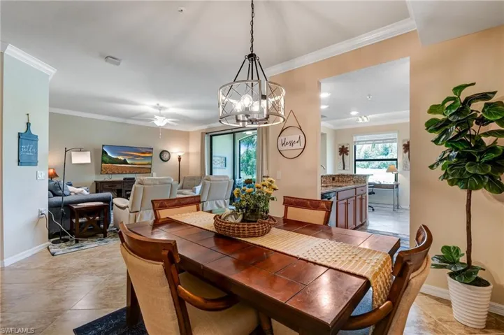 Dining area with crown molding, a ceiling fan, a chandelier, baseboards, and light tile patterned floors