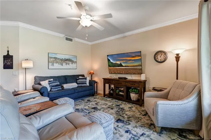 Living area featuring ornamental molding, a ceiling fan, and baseboards