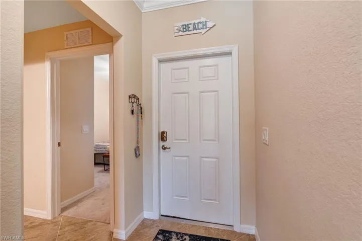 Entrance foyer with light tile patterned floors, a textured wall, and baseboards