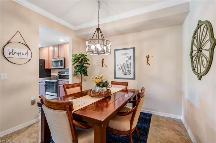 Dining space with a chandelier, ornamental molding, baseboards, and light tile patterned floors