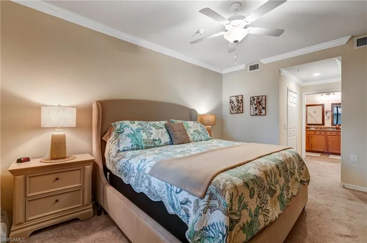 Bedroom with light carpet, crown molding, connected bathroom, baseboards, and a ceiling fan