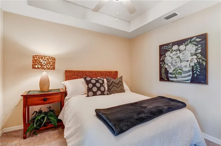 Carpeted bedroom with baseboards, a tray ceiling, and ceiling fan