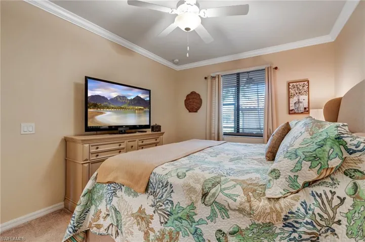 Bedroom with carpet floors, ornamental molding, baseboards, and a ceiling fan
