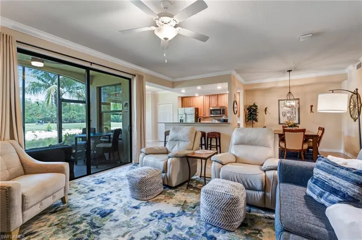 Living room featuring ornamental molding, a ceiling fan, and a chandelier