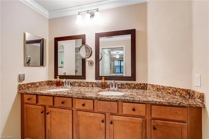 Bathroom with crown molding, double vanity, and a textured wall