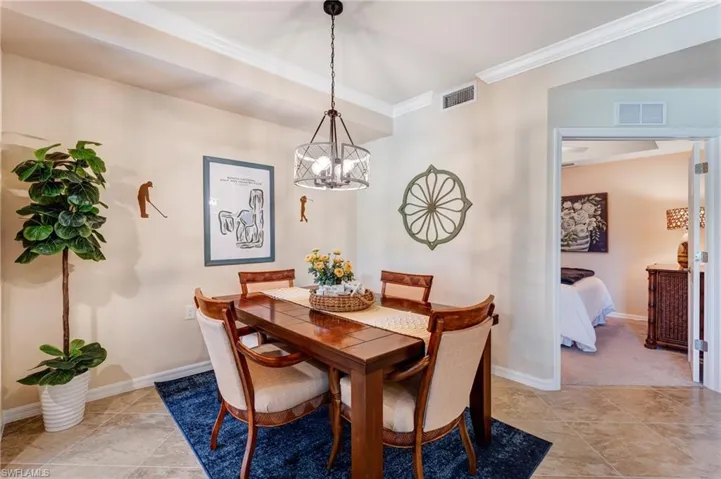 Dining area with a chandelier, ornamental molding, baseboards, and light tile patterned floors