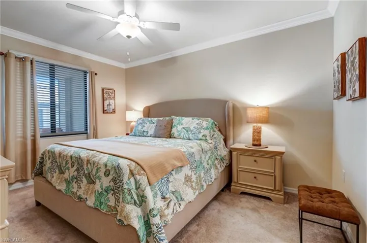 Bedroom with light carpet, ornamental molding, ceiling fan, and baseboards