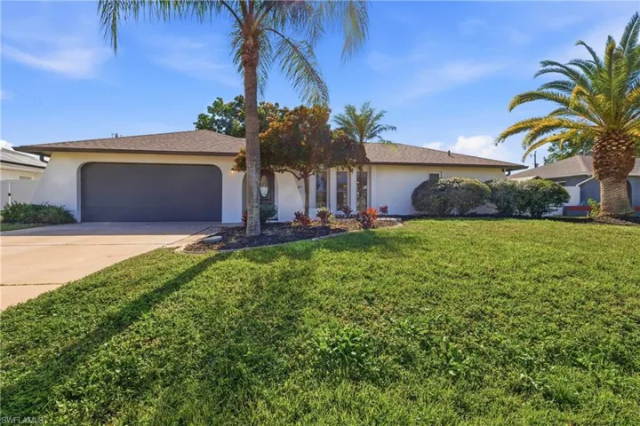 Ranch-style home featuring stucco siding, driveway, a front yard, and an attached garage