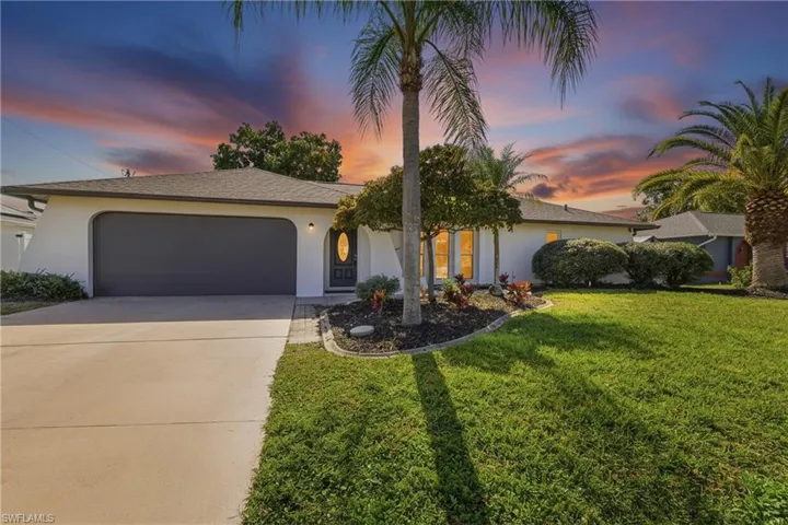 View of front of house featuring stucco siding, driveway, a yard, and a garage