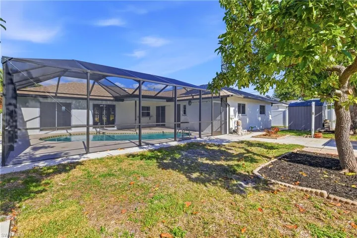 Back of house featuring a sunroom, a lanai, a patio, a yard, and an outdoor pool