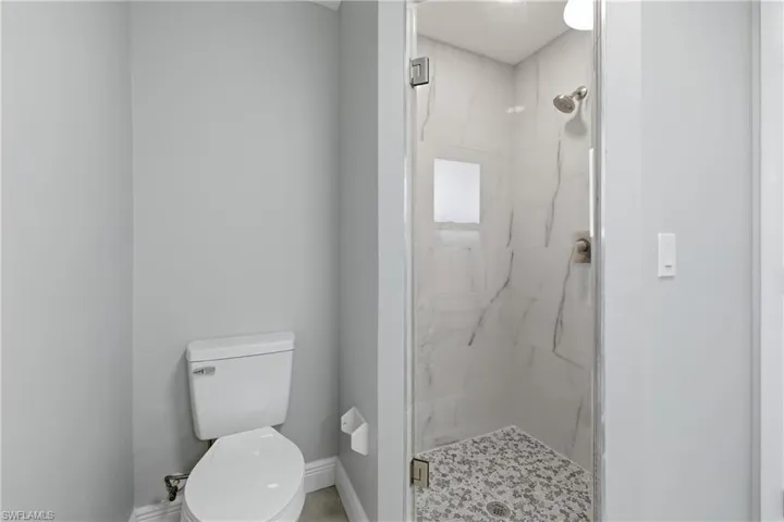 Bathroom featuring a marble finish shower and toilet
