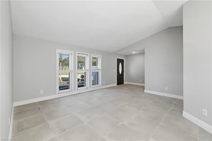 Spare room featuring lofted ceiling and baseboards