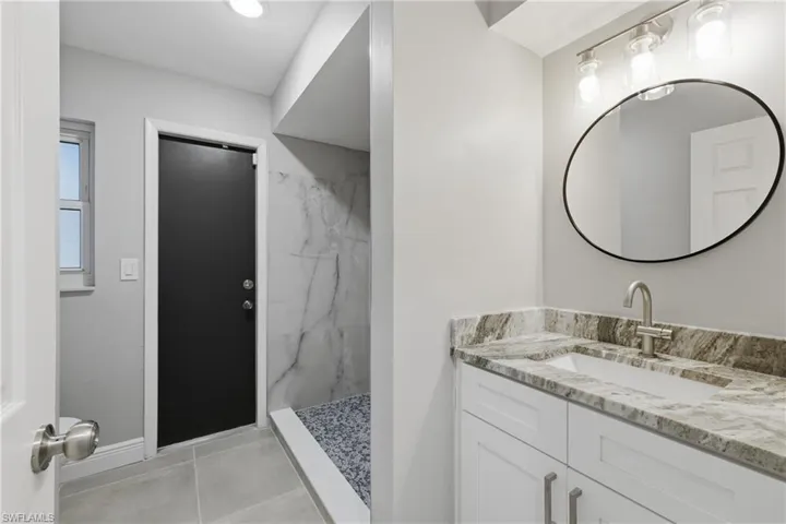 Bathroom featuring vanity and a marble finish shower