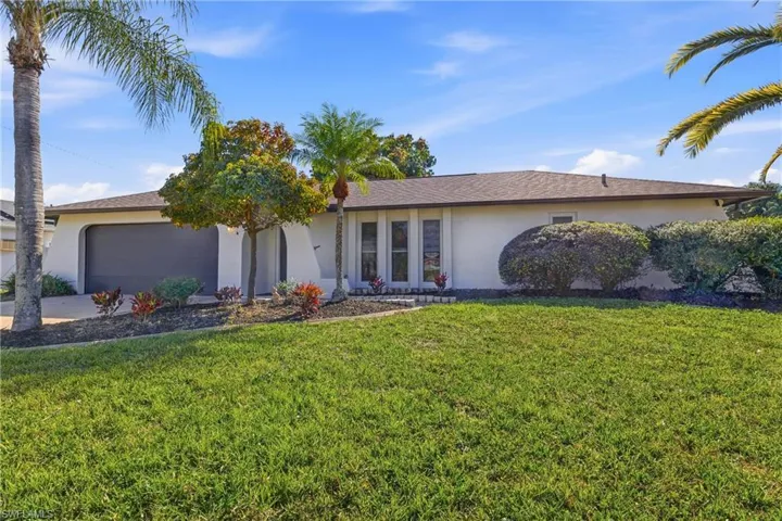 Single story home featuring stucco siding, a front lawn, an attached garage, and concrete driveway
