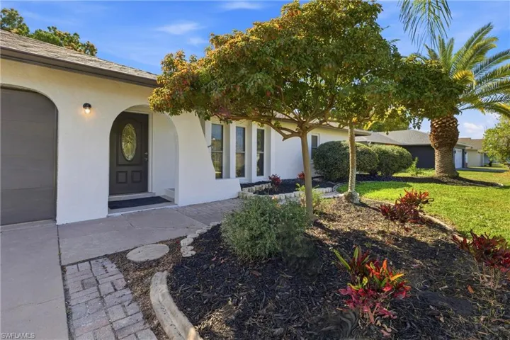 View of exterior entry with stucco siding and a lawn