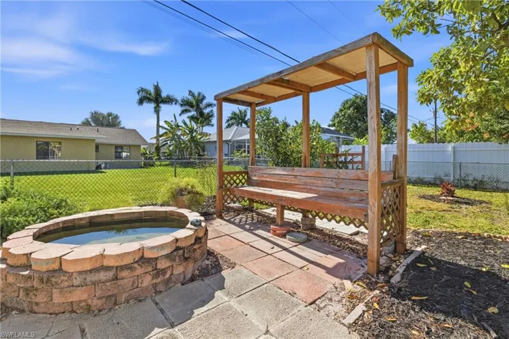 Fenced backyard featuring an in-ground hot tub and a patio