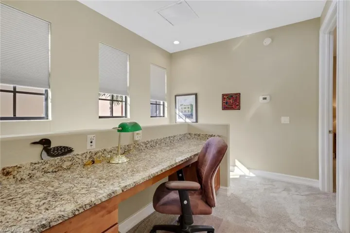 Home office featuring built in study area and light colored carpet